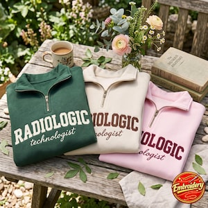 Op de afbeelding: Drie sweatshirts met een kwart rits in donkergroen, crème en lichtroze. Elk heeft de tekst RADIOLOGIC technologist in een collegiaal lettertype. Het groene sweatshirt heeft crèmekleurige tekst, het crème bruine tekst en het roze bordeauxrode.