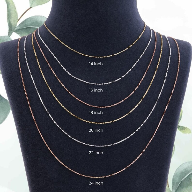 Op de afbeelding: Een display van zes delicate kettingkettingen in verschillende metallic afwerkingen, waaronder goud, zilver en ros&eacute;goud. Elke ketting is gelabeld met de lengte in inches, vari&euml;rend van 35,5 cm tot 61 cm. De kettingen worden gepresenteerd op een zwarte mannequin.
