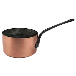 Puede incluir: Una cacerola de cobre con un mango largo y oscuro. La olla tiene una forma redondeada y un interior oscuro. El mango está unido al lateral de la olla con una junta remachada. La cacerola está diseñada para cocinar.