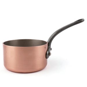 May include: A copper saucepan with a dark grey handle. The small pot has a rounded base and a single, curved handle attached with rivets. The interior of the pot is a darker, metallic colour.