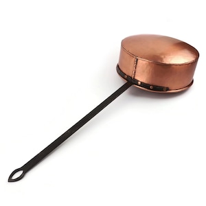 May include: A copper pot with a long, dark metal handle. The pot features a rounded, hammered body with a visible vertical seam and a dark metal band secured by rivets around the base. The handle ends in a teardrop-shaped loop for hanging.