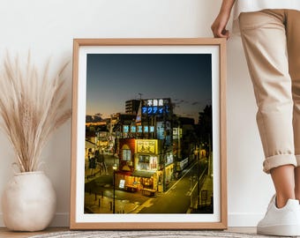 Op de afbeelding: Een ingelijste foto van een straatbeeld in Japan 's nachts. De gebouwen zijn verlicht met neonborden, waaronder een met de tekst "マクドナルド" (McDonald's). De straat is leeg, behalve een paar auto's.