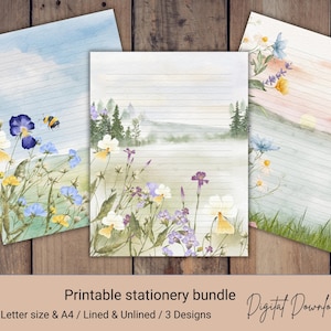 May include: Three sheets of printable stationery featuring watercolor illustrations. One sheet shows a blue sky with a bee and flowers, another depicts a forest landscape with wildflowers, and the third displays a sunset over a grassy field.