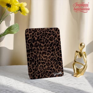 May include: A rectangular tablet or e-reader case featuring a brown and black leopard print pattern. The name Giselle is printed in white cursive script in the bottom right corner of the case. The case has a smooth, flat surface.
