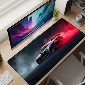 May include: A black and red extended mouse pad featuring a stylized image of a silver sports car drifting on a dark road. The car has black wheels and a rear spoiler. Red and white smoke effects are visible.