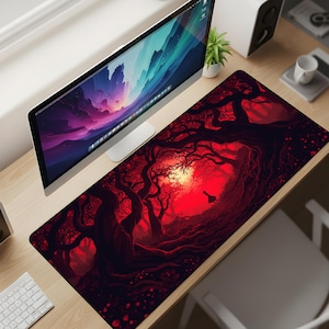 Puede incluir: Una alfombrilla de escritorio rectangular que presenta una escena de bosque oscuro y atmosférico con siluetas de árboles negros retorcidos sobre un fondo rojo vibrante. La ilustración muestra una fuente de luz brillante en lo profundo del bosque.