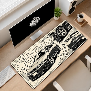 May include: A rectangular desk mat featuring a black and cream manga-style illustration of a sports car. The design includes multiple panels showing the vehicle from different angles, accented by bold Japanese katakana characters and exclamation marks.