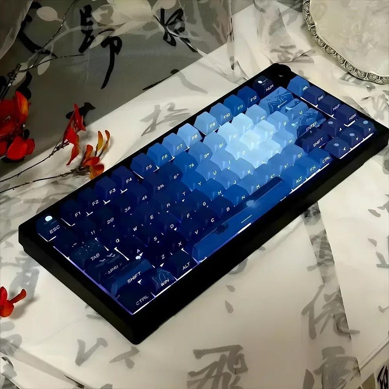 May include: A blue and black mechanical keyboard with a gradient of blue keycaps. The keyboard has a black frame and a white keycap with the word "ESC" on it.