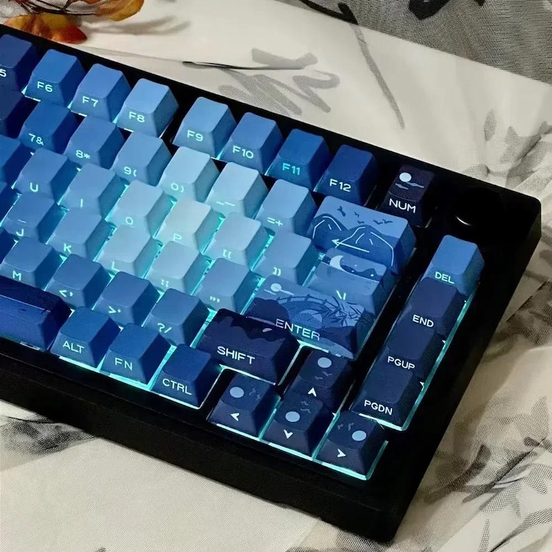 May include: A blue and white mechanical keyboard with a gradient color scheme. The keys have a variety of symbols and letters printed on them, including the numbers 5 through 12, the letters F6 through F12, and the words "NUM", "DEL", "END", "ENTER", "PGUP", "PGDN", "ALT", "FN", "CTRL", and "SHIFT".