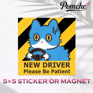 May include: A square sticker or magnet with a cartoon cat driving. The cat is blue with yellow eyes and a white face, holding a steering wheel. The background is yellow with black stripes, and the text reads "NEW DRIVER Please Be Patient."
