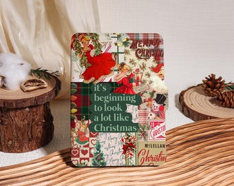 May include: A Christmas-themed decorative item with a collage design. The design includes vintage illustrations of women in red dresses, Christmas trees, and the text "it's beginning to look a lot like Christmas". The item is set on a wooden surface.