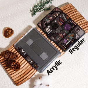 May include: Two tablet cases, one acrylic and one regular, displayed on a wooden surface. The regular case features a spooky illustration with potion bottles, skulls, and a cat. The acrylic case is gray with a stand. The word "Acrylic" and "Regular" are printed on the cases.