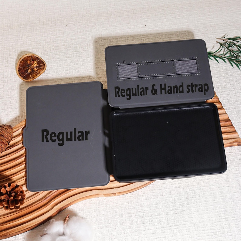 May include: A gray tablet case with the text "Regular" on the front cover and "Regular & Hand strap" on the inside cover. The case is open, revealing a black interior. The case is designed to protect a tablet.