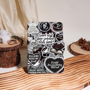 May include: A rectangular e-reader cover featuring a collage of dark-themed stickers, including skulls, roses, cherries, and text such as "Good girls love reading dirty books," "Villains have my heart," and "I read about psychos for fun."