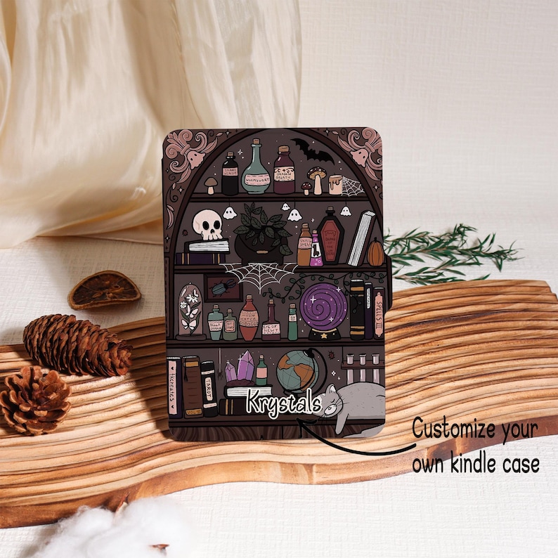 May include: A Kindle case featuring a dark bookshelf design with potion bottles, a skull, and a cat. The case has the text "Krystals" and "Customize your own kindle case". The case is designed with a spooky, witchy theme.
