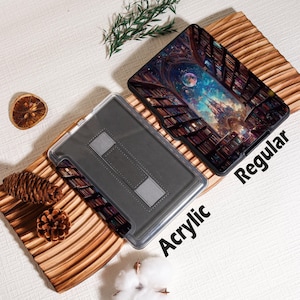 May include: Two tablet cases, one acrylic and one regular, are displayed. The regular case features a colorful fantasy scene of a library with a night sky and a castle. The acrylic case is clear with a gray interior and a stand.