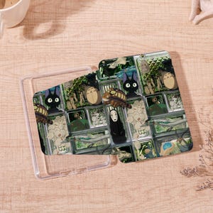 Peut inclure: Coque de téléphone transparente avec un motif coloré représentant des personnages du film d'animation "Mon voisin Totoro". Le motif comprend des images de Totoro, du Chatbus et d'autres personnages.