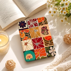 May include: A rectangular e-reader case featuring a grid of twelve distinct square panels, each displaying a unique floral illustration in shades of red, orange, yellow, cream, dark green, and navy blue against a white background.