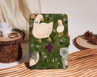 May include: A decorative case featuring a whimsical illustration of a goose and a gosling wearing blue bow ties, and two cats. The background is a green field with purple flowers. The case is likely for a tablet or phone.