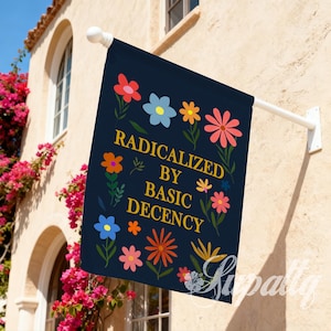 May include: A navy blue garden flag featuring a floral design and the text "RADICALIZED BY BASIC DECENCY" in gold. The flag is mounted on a white pole, suitable for outdoor use. The design includes various colorful flowers.