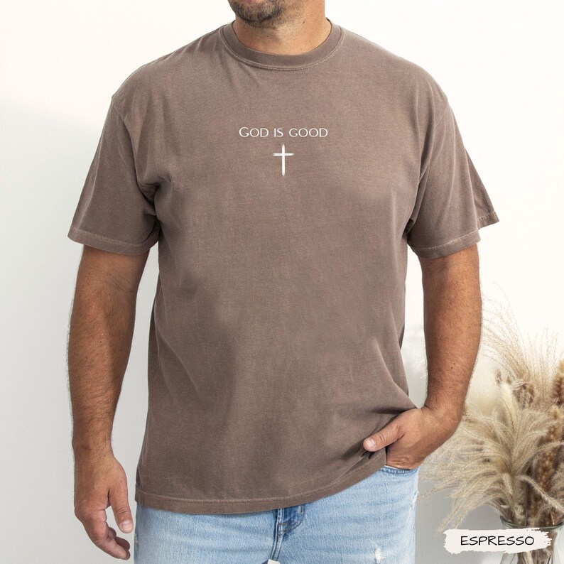 Peut inclure: T-shirt couleur expresso avec l'inscription "GOD IS GOOD" et une croix blanche. Le t-shirt &agrave; manches courtes est de couleur unie et a un col rond. Le t-shirt est fait d'une mati&egrave;re douce.