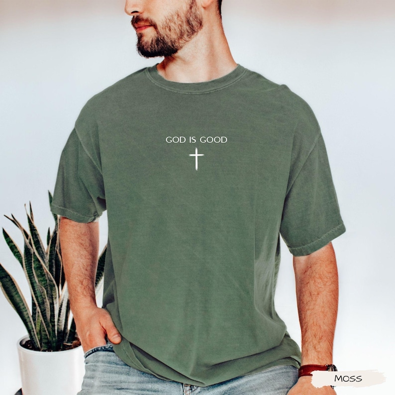 Peut inclure: T-shirt vert mousse avec l'inscription "GOD IS GOOD" et une croix blanche. Le t-shirt &agrave; manches courtes a une coupe d&eacute;contract&eacute;e. Le tissu semble doux et confortable.