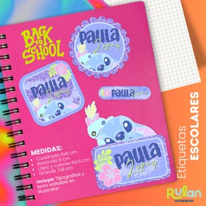 Puede incluir: Un cuaderno rosa con espiral con varias pegatinas con un personaje de dibujos animados azul y el nombre "Paula Lopez". Las pegatinas son de diferentes formas y tamaños, con el texto "Back to School" en verde. El cuaderno también tiene texto en español.