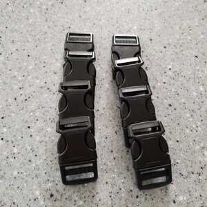 May include: Six black plastic buckle closures for straps or belts. The buckles are arranged in two stacks of three.
