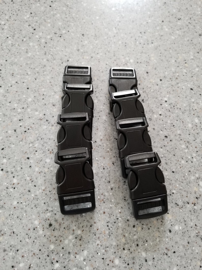 May include: Six black plastic buckle closures for straps or belts. The buckles are arranged in two stacks of three.