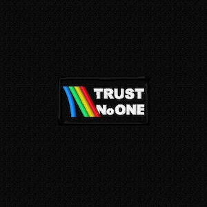 Peut inclure: Un écusson noir avec l'inscription blanche "TRUST No ONE". Un motif coloré de rayures bleues, vertes, rouges et jaunes se trouve sur le côté gauche du texte.