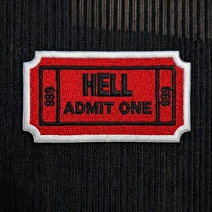 Op de afbeelding: Een rechthoekige geborduurde patch in de vorm van een ticket met een rode achtergrond, witte rand en zwarte stiksels. De tekst luidt HELL ADMIT ONE in het midden, met het getal 666 aan zowel de linker- als rechterkant van het ticket.