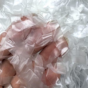 May include: A pile of clear, translucent rubber bands. The rubber bands are arranged in a random pattern and are all the same size.