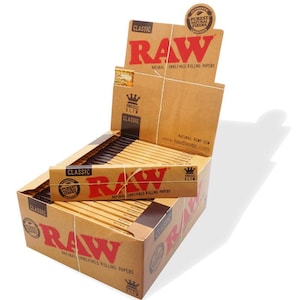 May include: A box of RAW Classic King Size Slim rolling papers. The box is brown with a red RAW logo and the text "Natural Unrefined Rolling Papers". The box is open and the papers are visible inside.