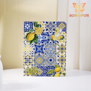 May include: A decorative notebook featuring a vibrant tile pattern in blue, yellow, and white. The design incorporates lemons, leaves, and a pitcher of lemonade. The notebook is on a white surface.