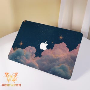 Op de afbeelding: Laptophoes met een ontwerp van een sterrenhemel, roze en blauwe wolken en gouden glitteraccenten. Het heeft een wit Apple-logo. De merknaam "Somypon" staat onderaan met een vlinderlogo.