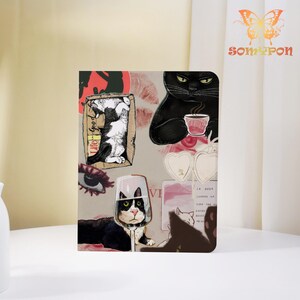 May include: A decorative notebook featuring a collage of cat illustrations. The design includes a black cat with a cup, a cat in a wine glass, and a cat in a box with the text "Life Good". The notebook has a light beige background.