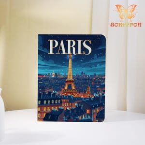 May include: A notebook featuring a nighttime illustration of Paris, with the Eiffel Tower prominently displayed. The word "PARIS" is written in large, gold letters at the top. The image has a blue and gold color scheme, with city lights illuminating the scene.