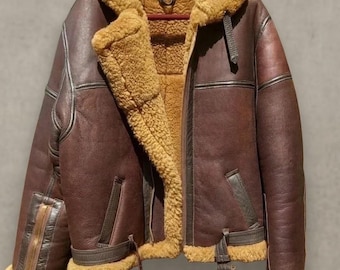 May include: A brown leather jacket with a shearling collar and lining. The jacket has a zip closure, pockets, and buckle details. The text "IYALEATHER" is visible at the bottom.