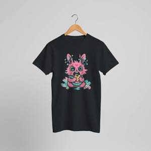 May include: Black t-shirt featuring a cartoon pink bunny with teal and pink accents, eating pizza. The bunny has decorative lights on its head. The design is whimsical and colorful.