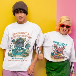 May include: Two people wearing white t-shirts with cartoon graphics. One shirt says "Sunburnt & Socially Overheated" with a bunny in sunglasses. The other says "Tinsel Tantrum Tour '25" with a pink bunny. The background is yellow and pink.