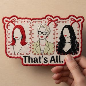 May include: Embroidered patch with three female figures, each in a separate frame, with red lips and hair. The text "That's All." is at the bottom. The patch is framed in red with bows. Held by a hand.