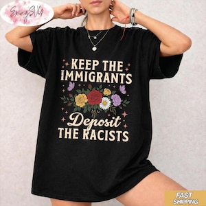 Puede incluir: Camiseta negra con el texto "KEEP THE IMMIGRANTS" sobre un ramo floral y "DEPOSIT THE RACISTS" debajo. El ramo incluye flores amarillas, rojas y blancas, con mariposas moradas. La camiseta es de estilo casual.