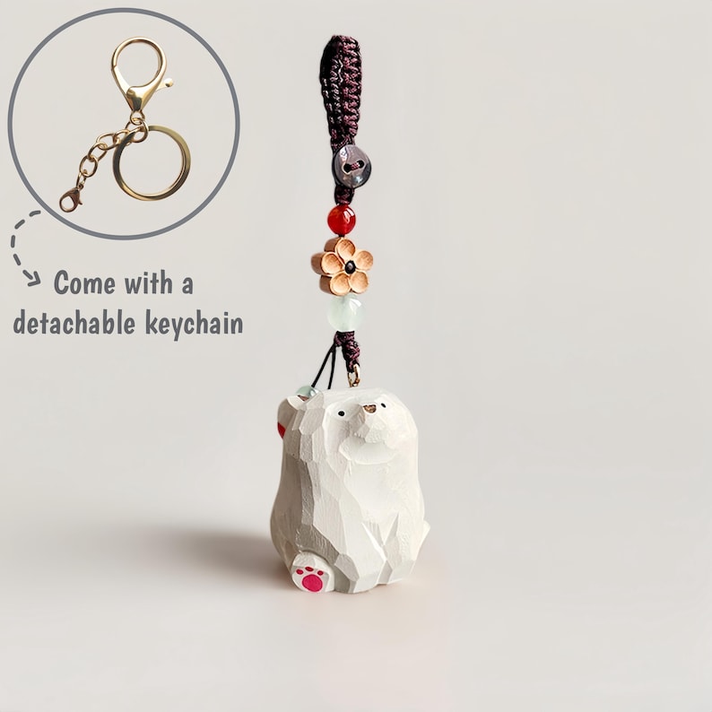 May include: A carved wooden bear keychain with a detachable gold-colored keychain. The bear is white with red accents on its paws and ears. The keychain has a decorative cord with beads and a flower charm. The text "Come with a detachable keychain" is also present.