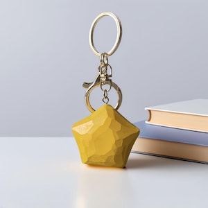 May include: A gold key chain with a yellow wooden star-shaped charm. The star has a faceted design.