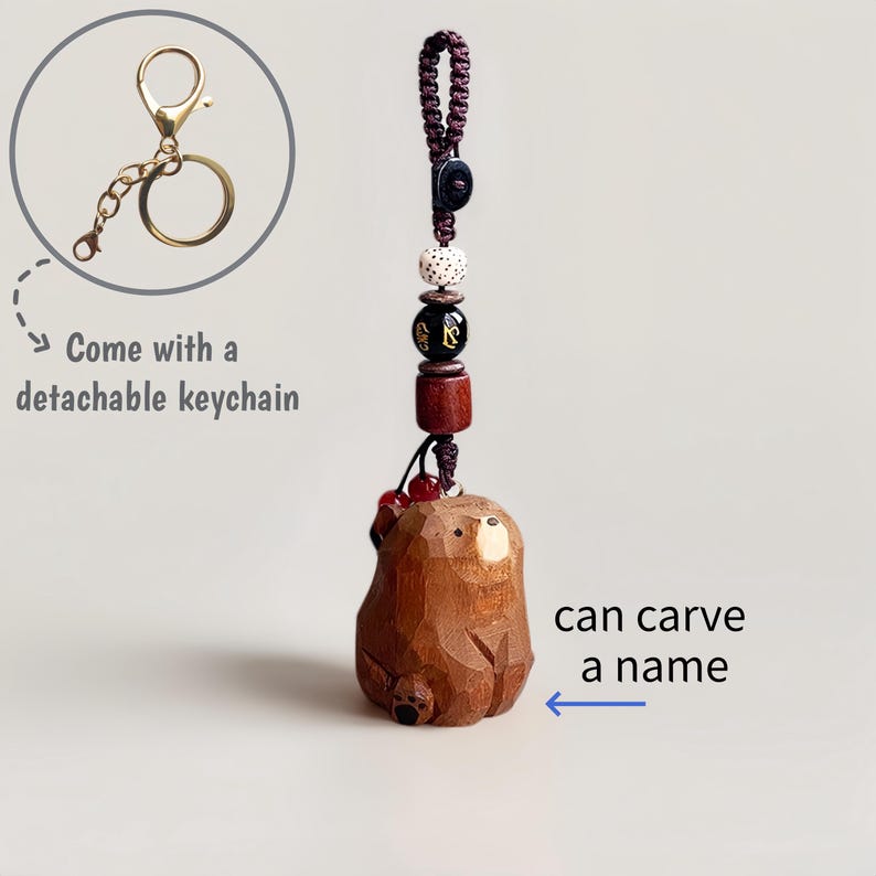 May include: A wooden bear keychain with a detachable gold-colored keychain. The bear is carved from wood and has a dark brown finish. The keychain includes decorative beads and the text "can carve a name".