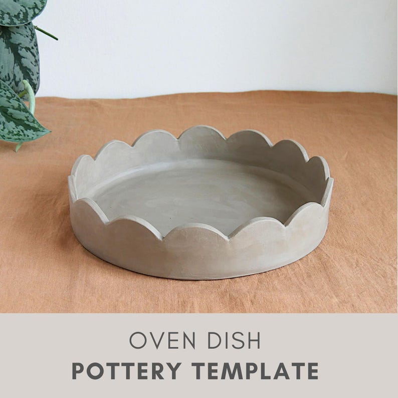 Op de afbeelding: Een ronde, lichtgrijze ovenschaal met een geschulpte rand. De schaal is gemaakt van een mat materiaal en staat op een bruinachtige ondergrond. De tekst "OVEN DISH POTTERY TEMPLATE" staat onderaan de afbeelding.