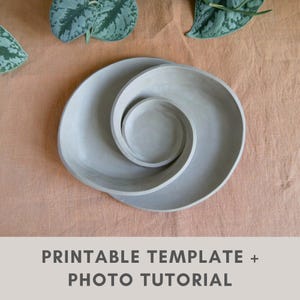Puede incluir: Un conjunto de tres platos de cerámica gris dispuestos en un diseño en espiral. Los platos están sobre una superficie de color melocotón, con hojas verdes en el fondo. El texto "PRINTABLE TEMPLATE + PHOTO TUTORIAL" está en la parte inferior.