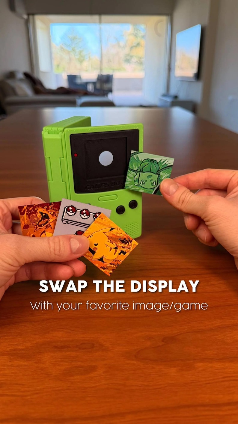 May include: A lime green handheld gaming device with a black screen and a selection of interchangeable display cards featuring Pok&eacute;mon characters. The text "SWAP THE DISPLAY" is visible.