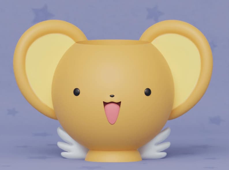 May include: A yellow ceramic planter shaped like a cartoon character with large ears, a smiling face, and a pink tongue sticking out. The planter has white wings on each side.