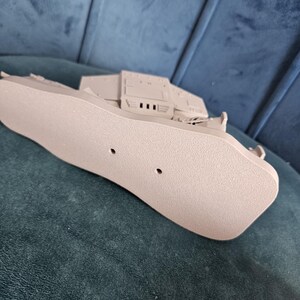 May include: A beige plastic model of a spaceship with a detailed underside. The model has two small holes on the bottom.